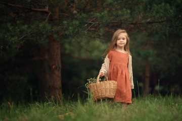 Full Length shot of caucasian girl with wicker basket standing in the green forest