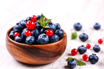 Fresh blueberries and red currants with mint leaves in a wooden bowl on burlap. Diet food, vegan berries