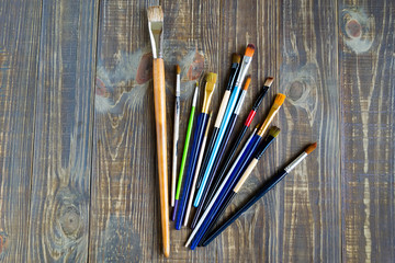 A variety of brushes for painting on a dark wooden background