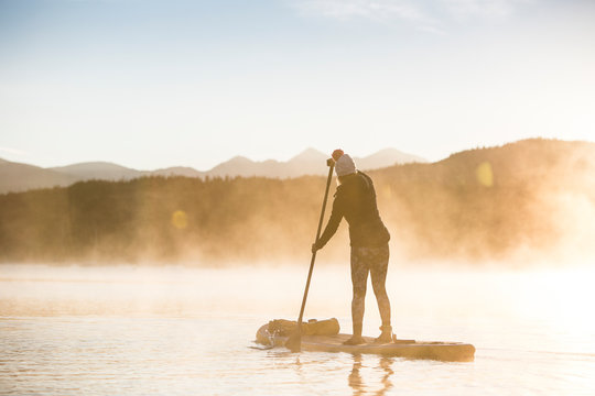 One woman paddle board on Lake Dillon in Summit County, Colorado in the early morning.         