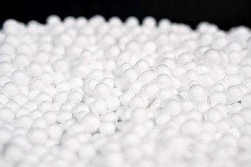 White Polystyrene foam beads on black background with copy space, waste cushioning material in...