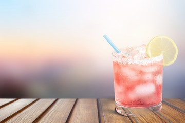 Delicious pink cocktail with ice and lemon on blurred background