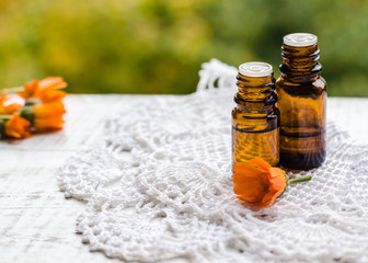 Calendula essential oil with fresh marigold flowers in a small glass bottle. Aromatherapy marigold oil. (Pot marigold extract, tincture, infusion)