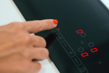 Closeup female hand turning on electric hob