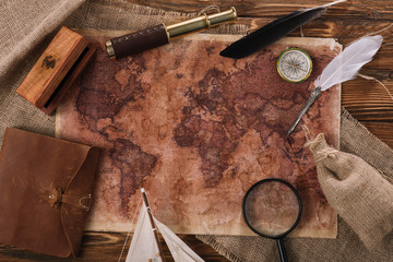 top view of old world map near telescope, nib and compass on wooden surface