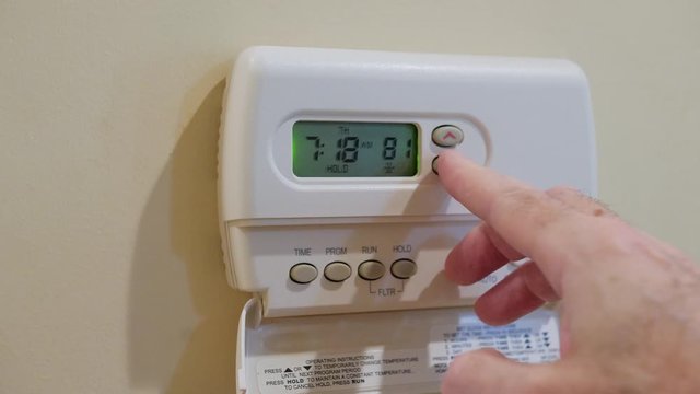 Setting digital home thermostat to cool and programming air conditioner. Adjusting room temperature to energy saving 78 degrees.