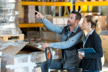 businesswoman with clipboard with warehouse worker