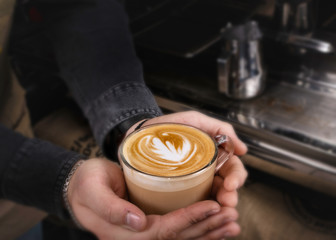 Barista makes latte coffee with milk in cafe closeup