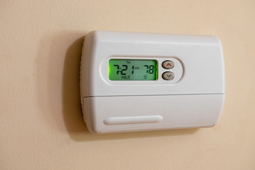 Programmable digital thermostat set to energy saving 78 degrees. Wall mounted temperature controller for home air conditioning and heating system. 