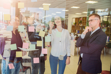 Obraz premium group of young businesspeople standing together in a modern office watching their manager draw a graph on a glass wall
