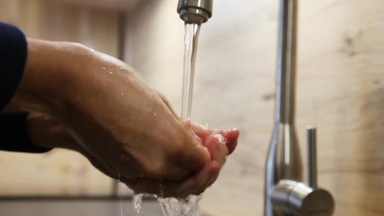 Woman is washing her hands in a newly decorated modern kitchen