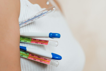 the girl holds several thermometers of different types at once, close up