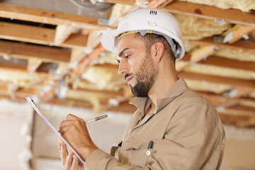 male builder writing on clipboard