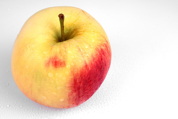 one ripe apple of bright yellow color with a reddish side is depicted on the left