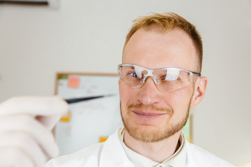 Man wearing white robe holding tweezers.