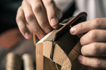 a tanner in a workshop makes a wallet from genuine leather in a special clip