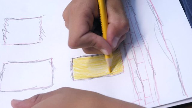 A child draws the house of his dreams on a sheet of paper.