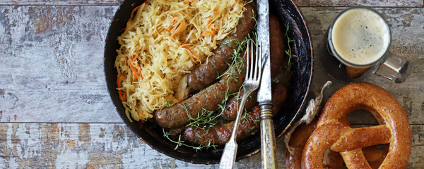 Banner. Oktoberfest food. Bavarian sausages and sauerkraut in a pan. Fresh Bavarian beer food. Oktoberfest celebration. Selective focus. Macro.