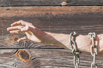 Men's hands tied with a metal chain