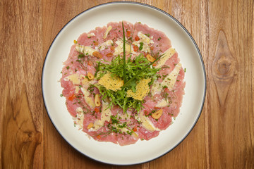 Tuna carpaccio with Italian herb dressing served on the wooden table. Exquisite dish. Creative restaurant meal concept.	