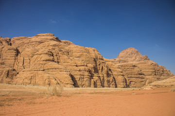 planet Earth world heritage touristic destination site Wadi Rum Jordan Middle East scenery landscape view sand valley foreground and picturesque mountain ridge on blue sky background 