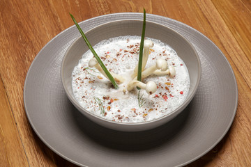Enoki cream soup in a ceramic bowl, close up. Exquisite dish. Creative restaurant meal. Fine dining concept.	