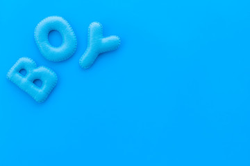 Boy word as decoration for baby shower on blue background top view frame copy space