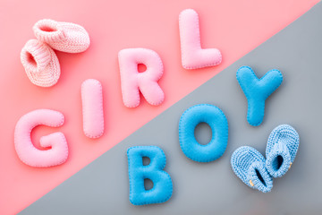 Naklejka premium Baby shower concept. Words boy and girl near booties on pink and blue background top view