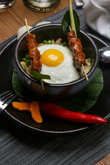 Nasi goreng - fried rice with chicken satay and a fried egg. Exquisite dish. Creative restaurant meal concept.