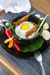 Nasi goreng - fried rice with chicken satay and a fried egg. Exquisite dish. Creative restaurant meal concept.