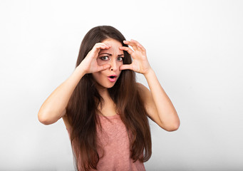 Beautiful angry grimacing woman prying and showing control sign holding hands near the eyes with...