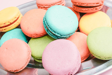 Fototapeta na wymiar A lot of french colorful macarons on a pink background