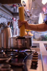 girl cooks spaghetti in a stainless steel pan