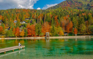 COPY SPACE: Woman sits on the pier with her dog and observes the stunning lake