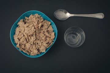 Cereal de fibra con fondo negro chuchara y vaso