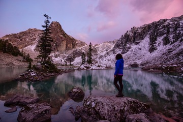 Fototapeta premium Adventurous Girl enjoying the View of a Glacier Lake in the Canadian Mountain Landscape during a colorful sunset in Fall. Taken in Watersprite Lake, Squamish, North of Vancouver, BC, Canada.