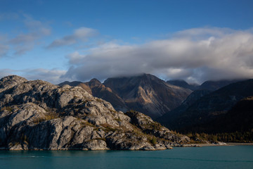 Naklejka na ściany i meble Beautiful View of American Mountain Landscape on the Ocean Coast during a cloudy and colorful morning in fall season. Taken in Glacier Bay National Park and Preserve, Alaska, USA.