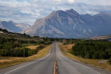 Beautiful View of Scenic Highway with American Rocky Mountain Landscape in the background during a Cloudy Summer Morning. Taken in St Mary, Montana, United States.