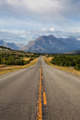 Beautiful View of Scenic Highway with American Rocky Mountain Landscape in the background during a Cloudy Summer Morning. Taken in St Mary, Montana, United States.