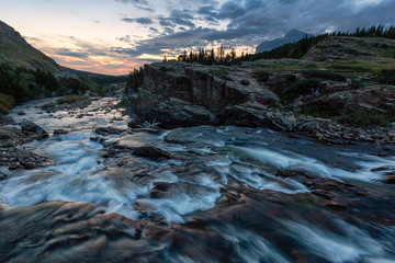 Beautiful View of the Glacier River during a cloudy morning sunrise in the American Rockies. Taken in Swiftcurrent Lake, Glacier National Park, Montana, United States.