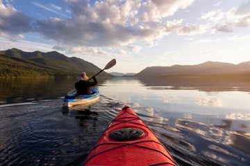 Adventurous Man Kayaking in Lake McDonald during a sunny summer evening with American Rocky...