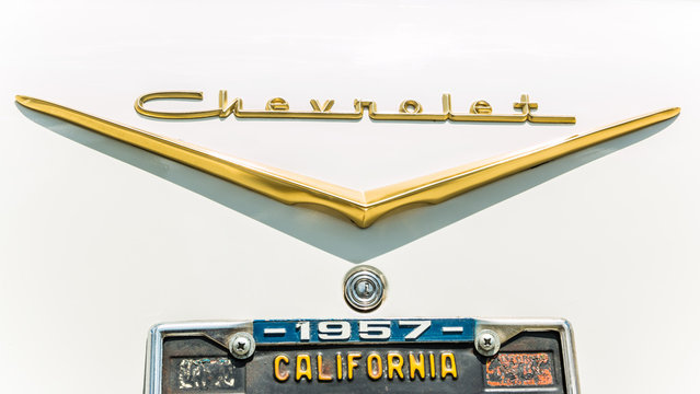 The rear trunk nameplate on a white 1957 Chevrolet with gold trim and a California license plate.
