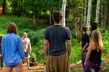 Diverse people enjoy spiritual gathering A multigenerational group of individuals are seen standing in a circle in a forest clearing as they practice shamanic and native traditions in nature.