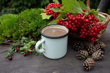 Obraz na płótnie Canvas wild berries, cones and a mug with a drink