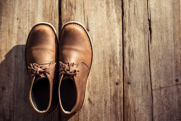 Brown stylish boots on wood background,  retro color