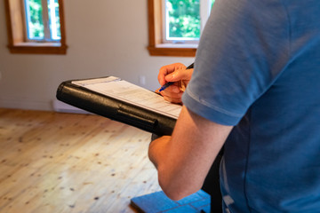 Indoor damp & air quality (IAQ) testing. A close up view on the arms and hands of a man filling in...