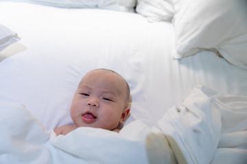 Cute asian baby lies in a white round bed