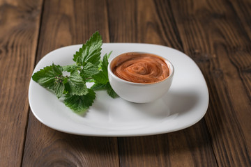 A sprig of fragrant grass and a red-and-white sauce on a wooden table. Vegetarian sauce.