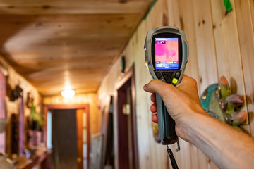 Indoor damp & air quality (IAQ) testing. A closeup view of a man using a thermovision spot camera...