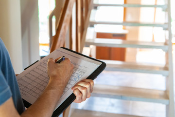 Indoor damp & air quality (IAQ) testing. A closeup view on the hands of a building inspector, filling in forms & paperwork, checking regulations are met inside a residential dwelling, with copy-space. © Valmedia
